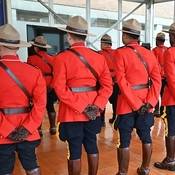 Photo de plusieurs membres de la GRC (vus de dos) portant la tunique rouge à l’intérieur