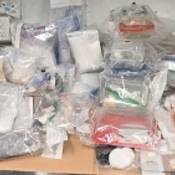 Dozens of clear evidence bags filled with various drugs and items on a desk.