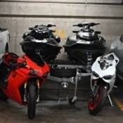 A high-end pick up truck parked beside two Ducati motorcycles, two Sea-Doos and a high-end sedan parked in an underground garage.