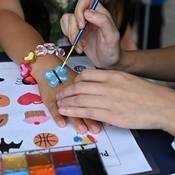 A youth getting their hand painted with a blue butterfly.