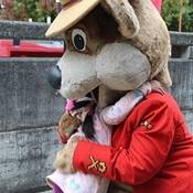 Safety Bear kneeling down hugging a little girl wearing a pink dress.