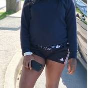 Photo of Shanique Bryan standing outside, wearing a black t-shirt and black shorts