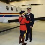 Surintendante principal Ellis remet la médaille au pilote de la GRC, l'agent spécial Allen Predovic. Un avion de la GRC est visible à l'arrière-plan.