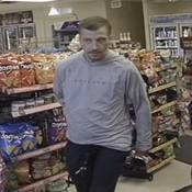 Unknown individual #1, a man with short brown hair, and a goatee. He is seen wearing a grey hoodie with black lettering across the chest and a pair of black pants;