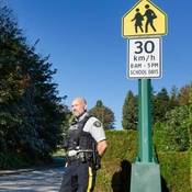 RCMP officer conduct speed enforcement in a school zone with 30 km/hr speed sign in the top right corner