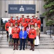 Photo de groupe de certains des récipiendaires de la médaille de la Division M, certains portant l'uniforme de tunique rouge, debout en quatre rangées, avec la commissaire du Yukon, Adeline Webber, debout au milieu de la première rangée.