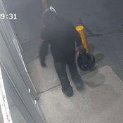 Un individu portant un casque et un chandail noir, rouge et blanc vu de dos.