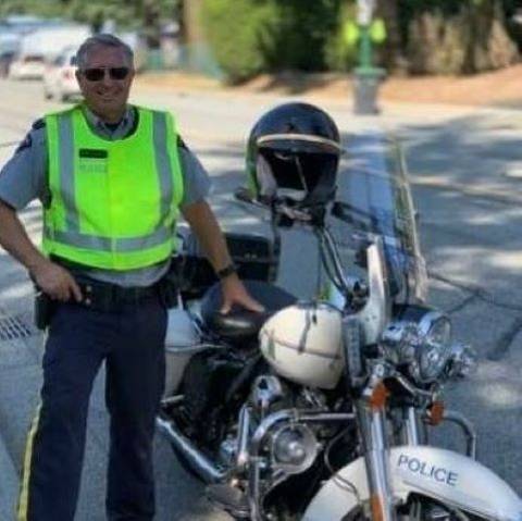 RCMP Traffic Service Supervisor conduct speed enforcement with a white RCMP motorcycle to his right