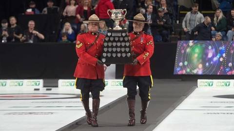 Photo of two RCMP officers in red serge carrying the Brier championship trophy