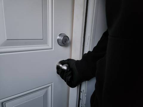 Person dressed in all black opening a door.
